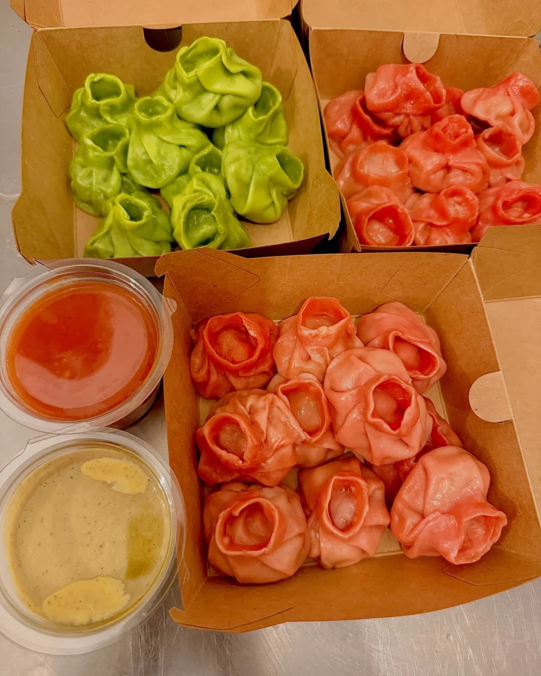 Momos verts et roses dans leurs boîtes, avec les deux sauces maison
